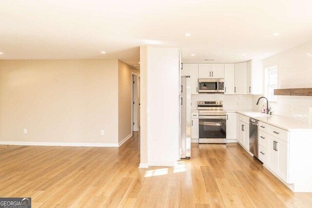 kitchen with stainless steel appliances, light hardwood / wood-style floors, white cabinets, and sink