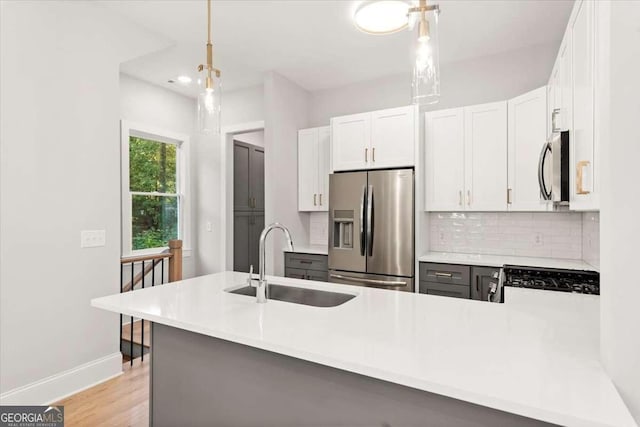 kitchen featuring kitchen peninsula, sink, decorative light fixtures, stainless steel fridge with ice dispenser, and white cabinetry