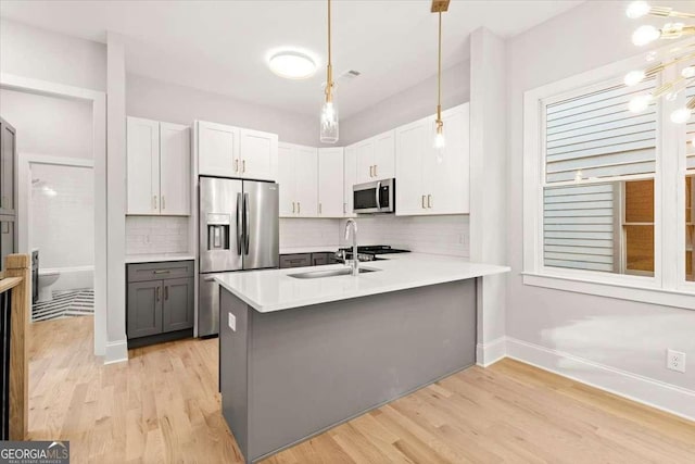 kitchen with kitchen peninsula, white cabinets, stainless steel appliances, and decorative light fixtures