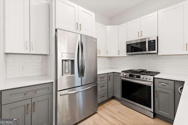 kitchen with white cabinets, gray cabinets, stainless steel appliances, and tasteful backsplash