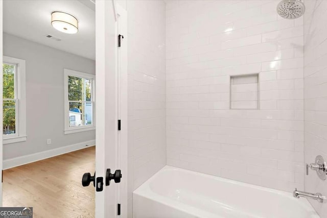 bathroom featuring shower / tub combination, plenty of natural light, and hardwood / wood-style flooring