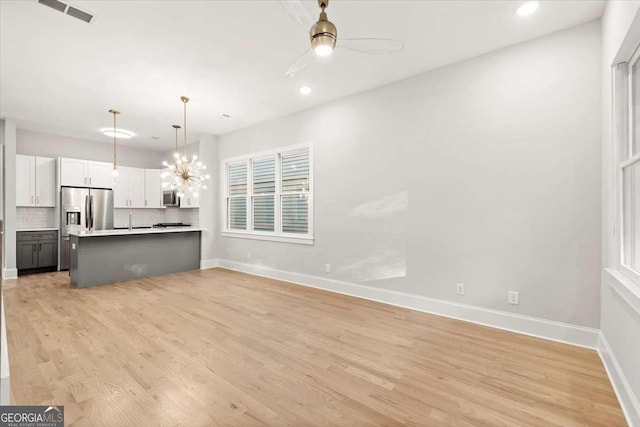 kitchen with white cabinets, ceiling fan with notable chandelier, tasteful backsplash, decorative light fixtures, and stainless steel appliances