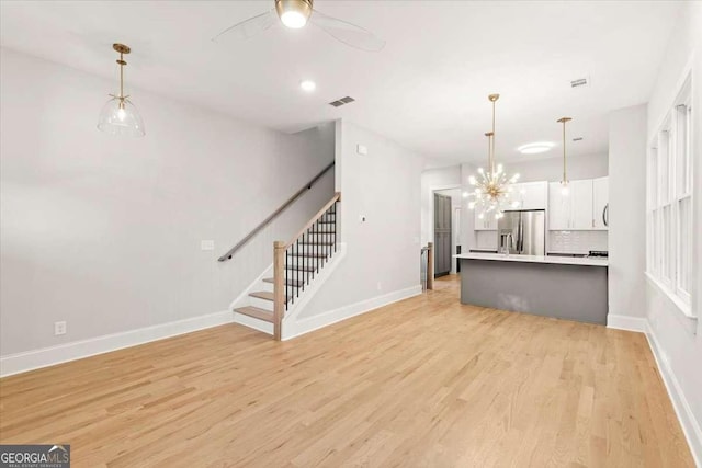 unfurnished living room with a chandelier and light hardwood / wood-style floors