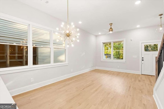 unfurnished dining area featuring light hardwood / wood-style floors and ceiling fan with notable chandelier