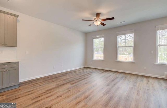 empty room with plenty of natural light, light hardwood / wood-style floors, and ceiling fan