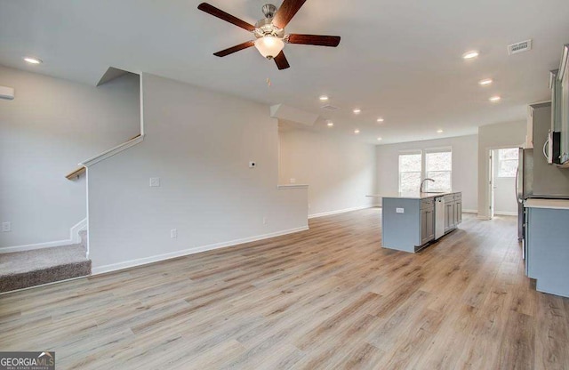 interior space featuring gray cabinetry, ceiling fan, dishwasher, light hardwood / wood-style flooring, and a kitchen island with sink