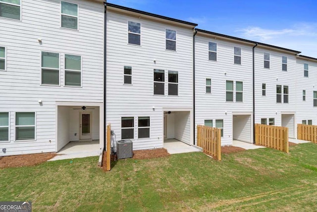 rear view of property with central AC unit, a patio, and a lawn