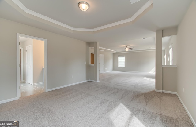 unfurnished room featuring light carpet, a raised ceiling, and crown molding