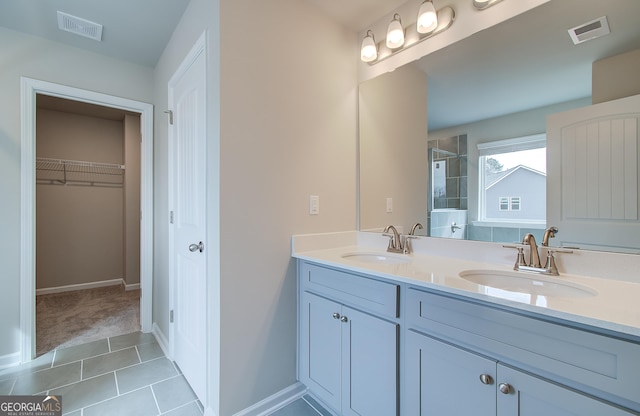 bathroom with tile patterned flooring, vanity, and walk in shower