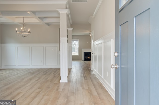 entryway with coffered ceiling, light wood-type flooring, ornate columns, beam ceiling, and a chandelier