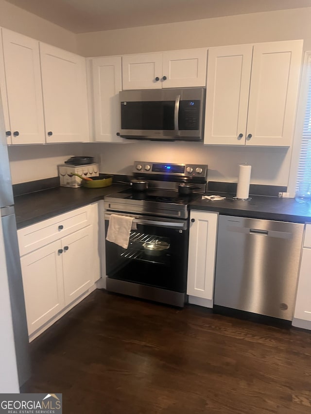 kitchen with white cabinetry, appliances with stainless steel finishes, and dark wood-type flooring