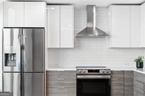 kitchen with white cabinets, stainless steel appliances, and wall chimney range hood