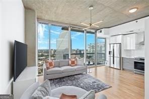 living room with light wood-type flooring, a wall of windows, and ceiling fan