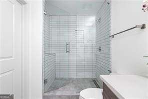 bathroom featuring vanity, a shower with shower door, and toilet