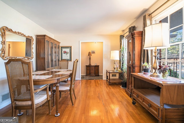 dining space with visible vents, light wood-style flooring, and baseboards