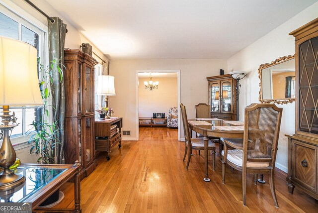 dining area featuring a chandelier, light wood-type flooring, visible vents, and baseboards