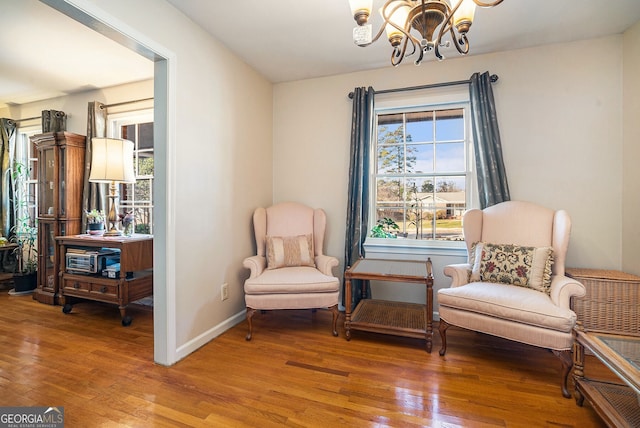 sitting room with a notable chandelier, baseboards, and wood finished floors