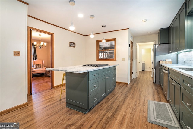 kitchen featuring a kitchen island, appliances with stainless steel finishes, wood finished floors, and ornamental molding