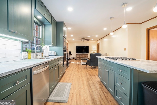 kitchen with appliances with stainless steel finishes, green cabinetry, a sink, and crown molding