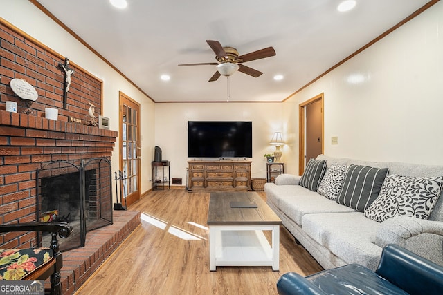 living room featuring crown molding, a fireplace, ceiling fan, and wood finished floors