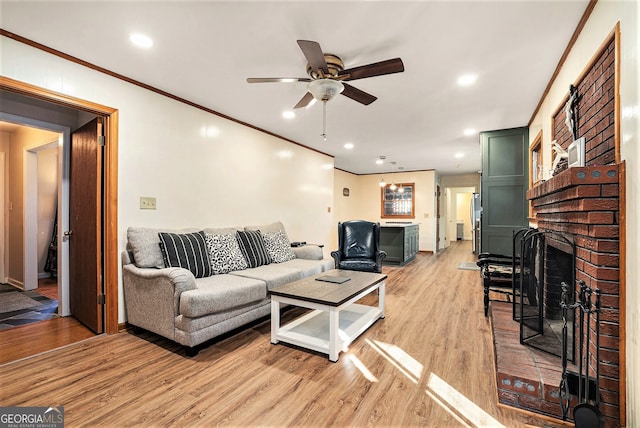 living room featuring ceiling fan, crown molding, light wood-style floors, a fireplace, and recessed lighting