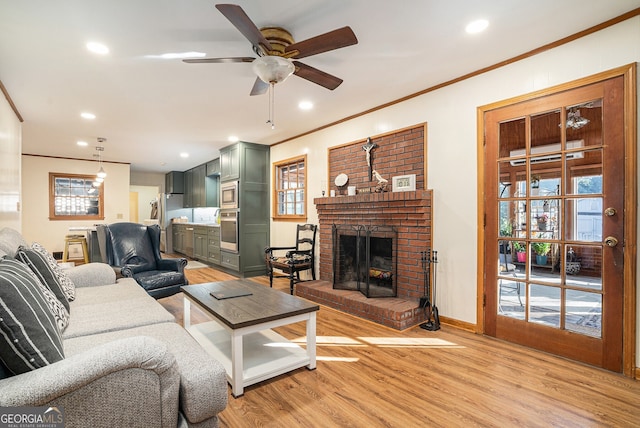 living room with ornamental molding, recessed lighting, a brick fireplace, and light wood-style flooring