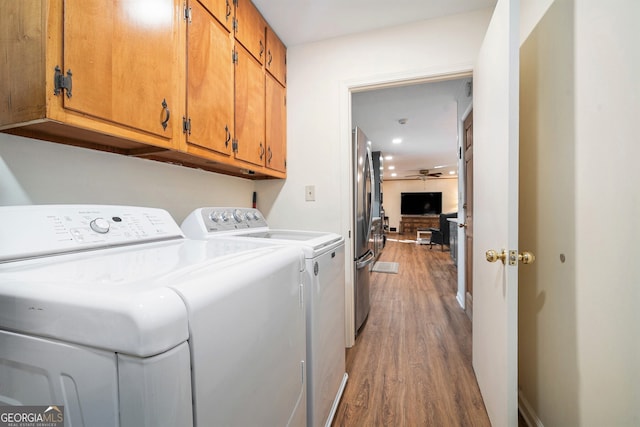 laundry area featuring a ceiling fan, cabinet space, washing machine and clothes dryer, and wood finished floors