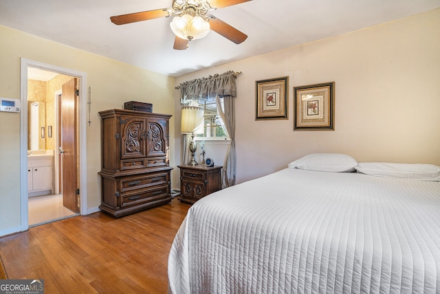 bedroom featuring ceiling fan, baseboards, wood finished floors, and connected bathroom