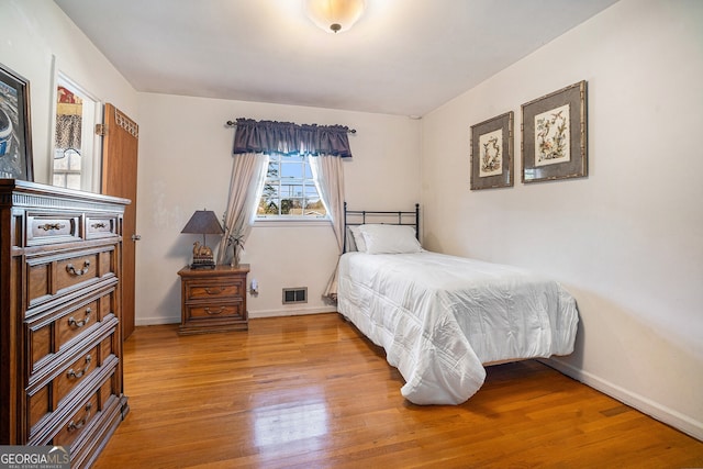 bedroom featuring visible vents, baseboards, and wood finished floors