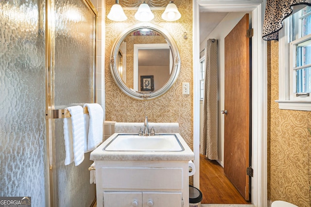 bathroom with wallpapered walls, wood finished floors, and vanity