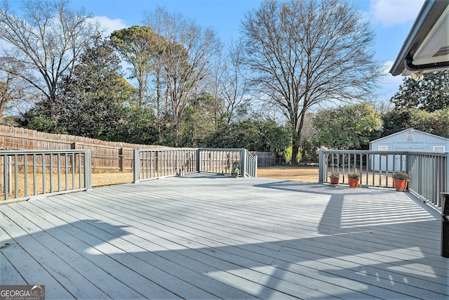 wooden deck featuring a fenced backyard and an outbuilding