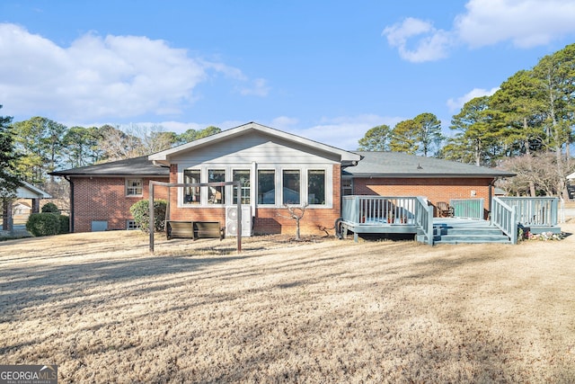 back of house with brick siding, a yard, and a wooden deck