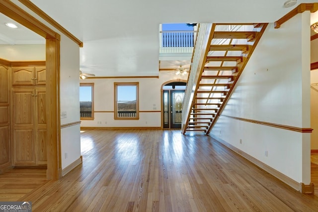 unfurnished living room featuring ceiling fan, crown molding, and light wood-type flooring