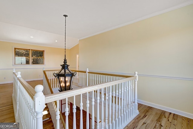 hall featuring a notable chandelier, light hardwood / wood-style floors, ornamental molding, and vaulted ceiling