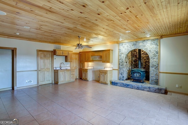 unfurnished living room featuring a wood stove, wooden ceiling, crown molding, ceiling fan, and light tile patterned flooring