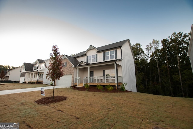 view of front facade with covered porch, a garage, and a front yard