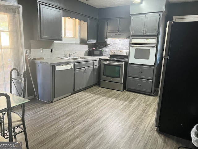 kitchen featuring gray cabinetry, sink, light hardwood / wood-style flooring, and appliances with stainless steel finishes