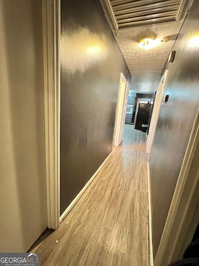 corridor with hardwood / wood-style floors and a textured ceiling