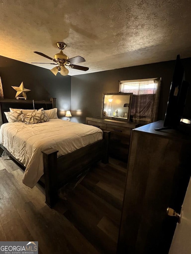 bedroom with ceiling fan, wood-type flooring, and a textured ceiling