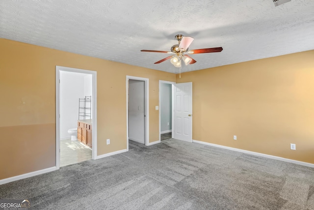 unfurnished bedroom featuring carpet flooring, ensuite bath, ceiling fan, and a textured ceiling