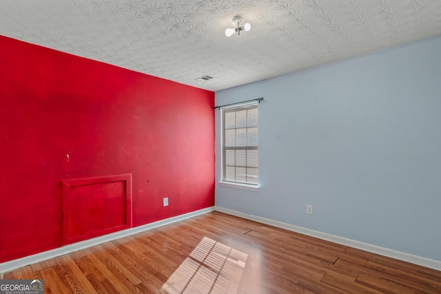 unfurnished room with a textured ceiling and hardwood / wood-style flooring