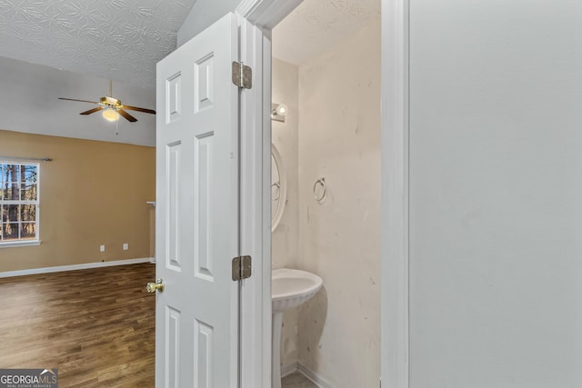 bathroom featuring hardwood / wood-style floors, ceiling fan, lofted ceiling, and a textured ceiling