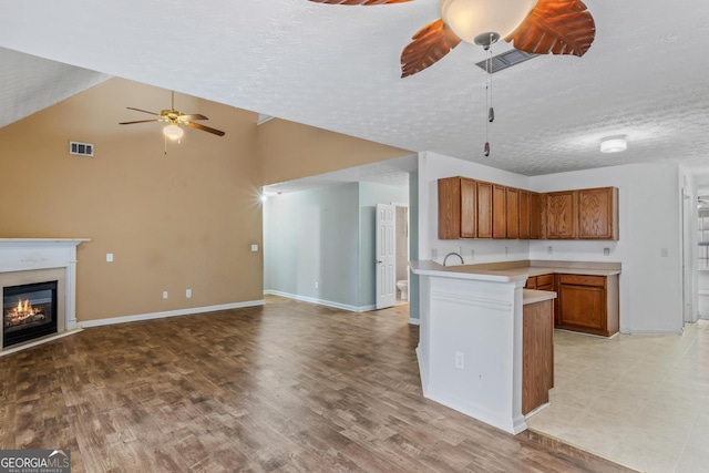 kitchen with ceiling fan, sink, kitchen peninsula, light hardwood / wood-style floors, and a textured ceiling