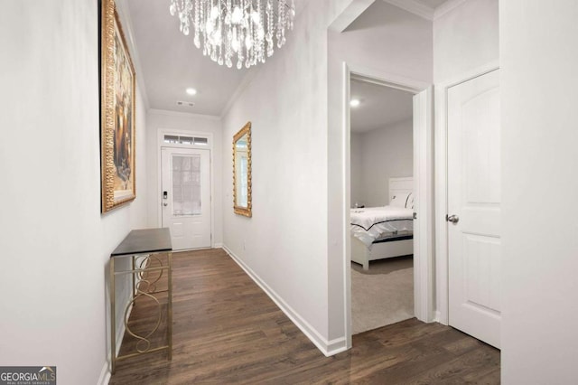 corridor with dark hardwood / wood-style flooring, a chandelier, and ornamental molding