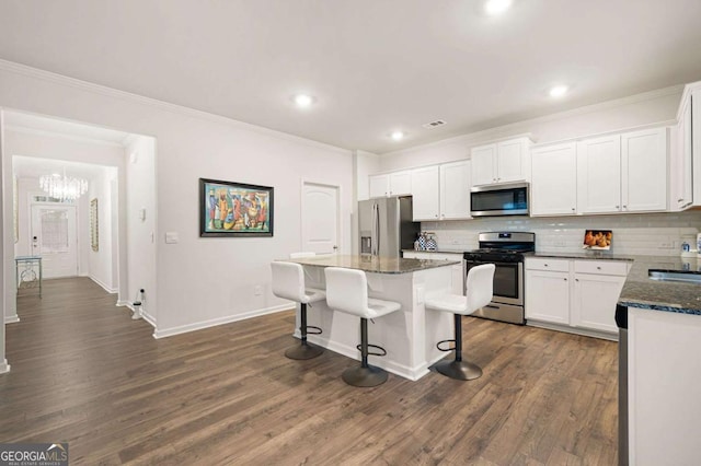 kitchen featuring tasteful backsplash, stainless steel appliances, a kitchen island, and white cabinetry