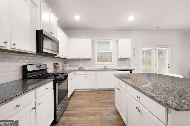 kitchen with dark stone countertops, white cabinets, and appliances with stainless steel finishes