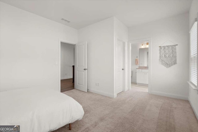 bedroom with light carpet and ensuite bath