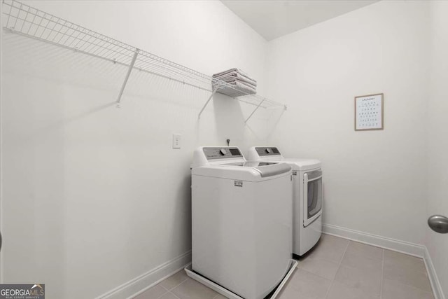 clothes washing area with washing machine and clothes dryer and light tile patterned floors