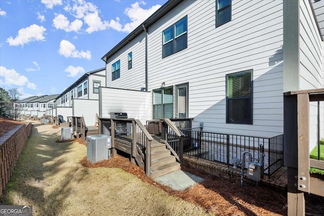 rear view of property featuring central AC and a wooden deck