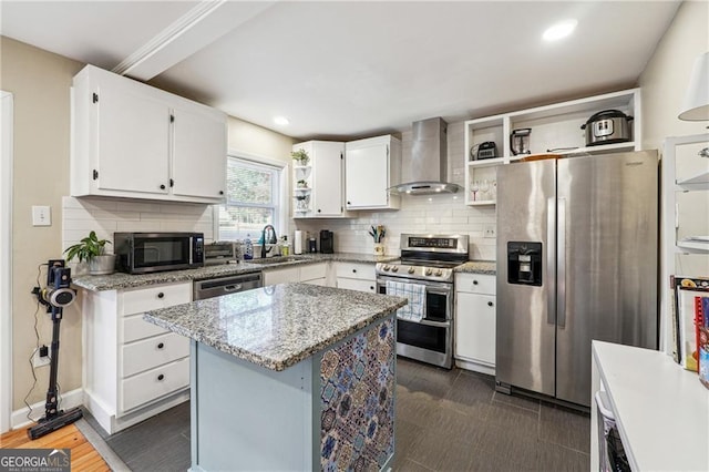 kitchen with sink, white cabinets, a center island, stainless steel appliances, and wall chimney range hood